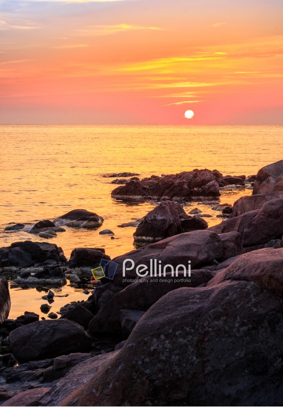 warm and calm sunrise over the rocky sea shore with huge boulders