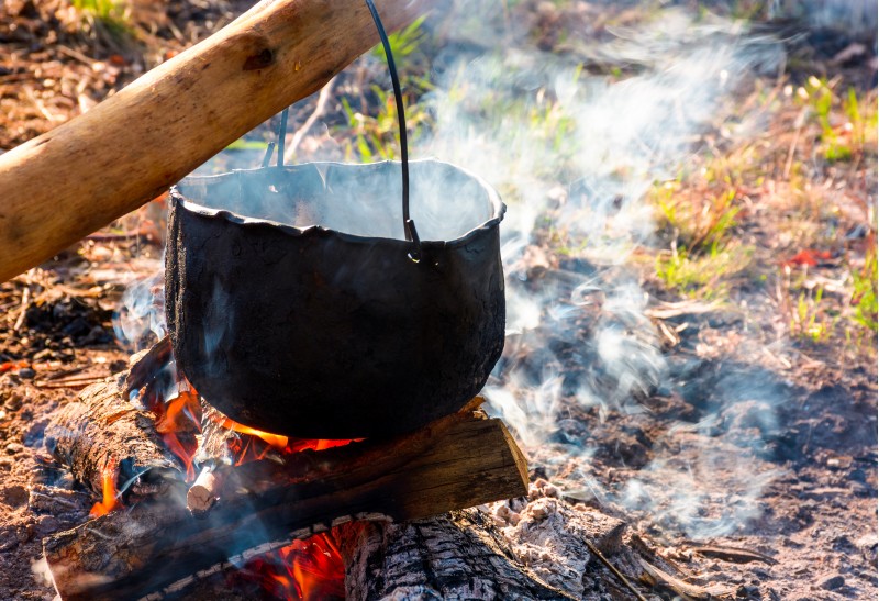 cauldron in steam and smoke on open fire. outdoor cooking concept. old fashioned way to make food