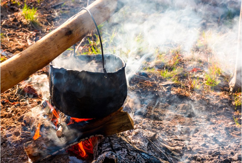 cauldron in steam and smoke on open fire. outdoor cooking concept. old fashioned way to make food