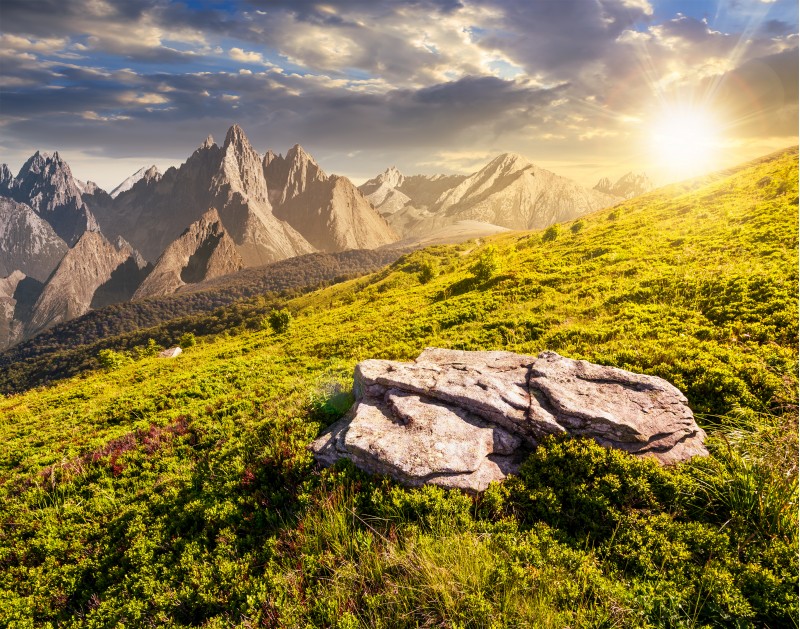 composite of meadow in rocky mountains at sunset. beautiful unrealistic landscape in summertime 