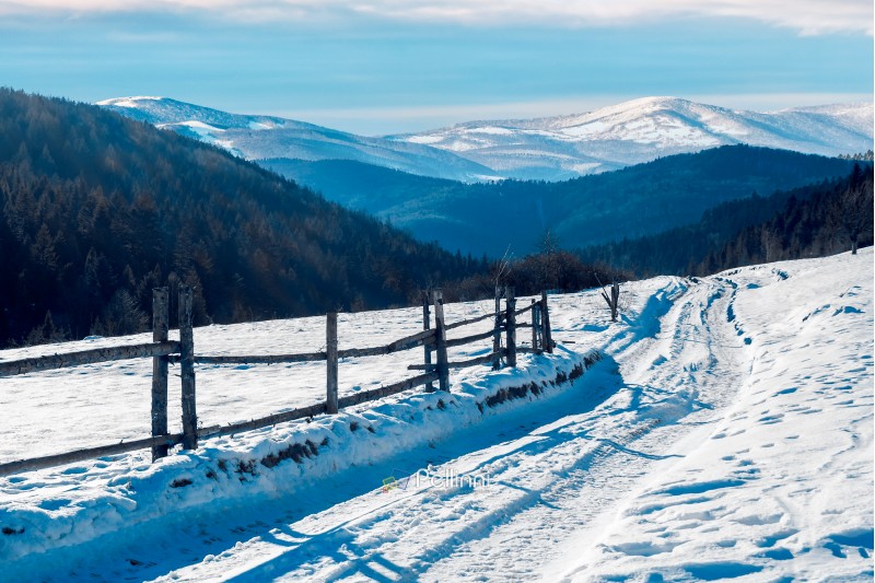 country road in to the winter mountains. wooden fence along the road. composite image