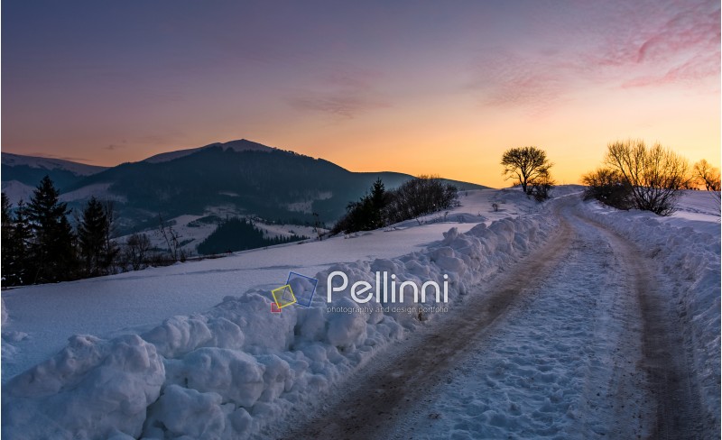 countryside road uphill in snow at sunset. beautiful winter scenery in mountainous area