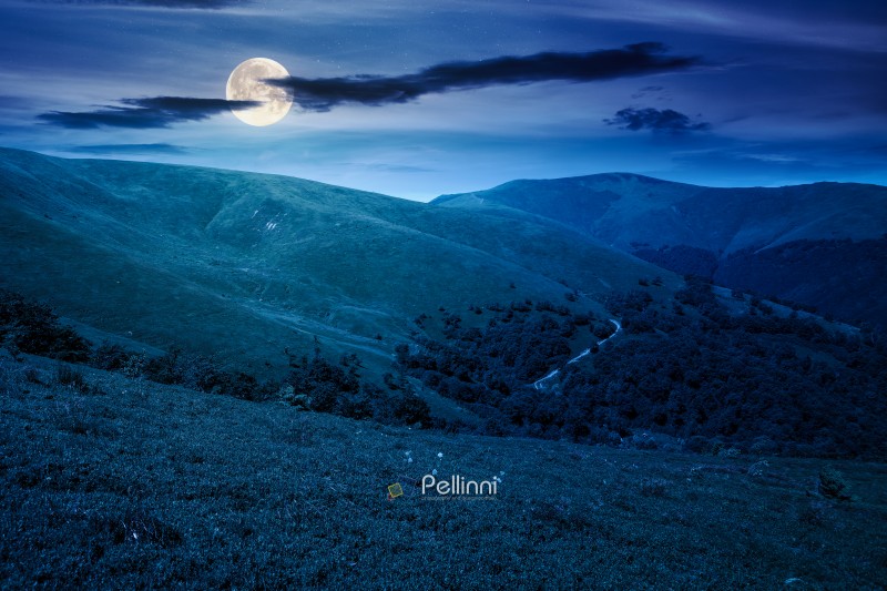 discover the beauty of mountain landscape in summer at night. scenic travel background with rolling hills and steep slopes in full moon light. alpine environment under dark blue sky.
