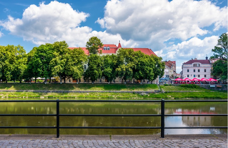 Uzhgorod, Ukraine - Jun 15, 2017: embankment of Uzh river in summer. Beautiful architecture and blossoming linden trees on fine weather day. Korzo street can be seen in the distance