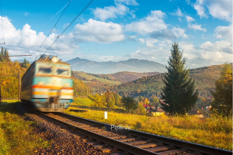 fast moving train in autumn mountains. wonderful autumn countryside at sunrise. village down in the valley. beautiful sky over the distant ridge