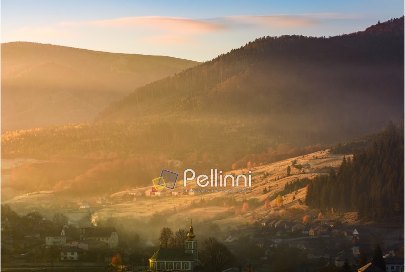 foggy sunrise in mountainous countryside. gorgeous autumnal landscape with village in mountains in fine weather
