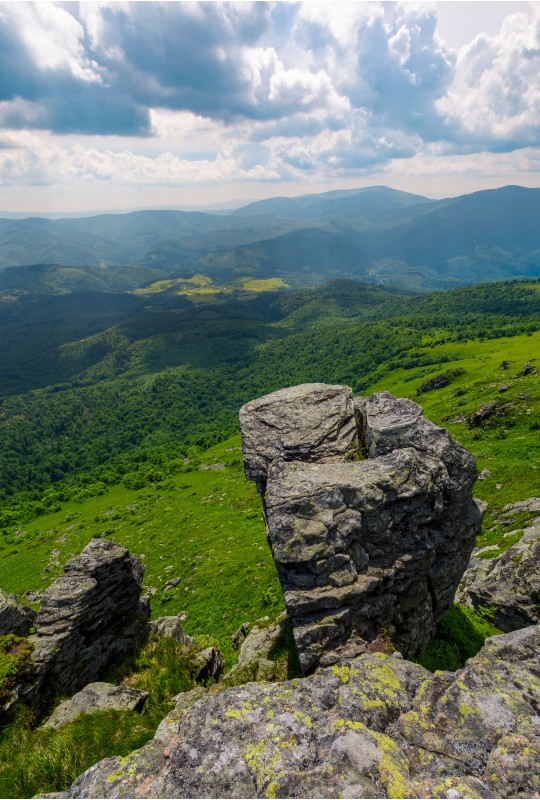 giant boulder on a cliff over the grassy hillside. beautiful summer landscape in Carpathian mountains on a cloudy day