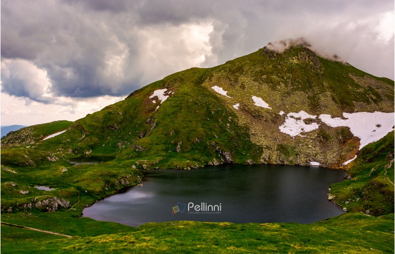 glacier lake Capra at the foot of the mountain. lovely summer scenery on a cloudy day. popular travel destination in Southern Carpathian mountains of Romania