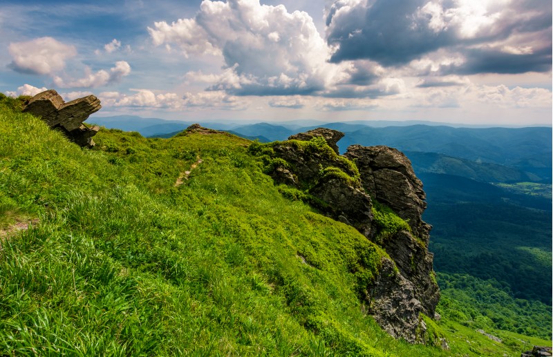 grassy hillside over the cliff in mountains. beautiful mountain ridge in the distance. viewing location mountain Pikui. gorgeous landscape of Carpathians