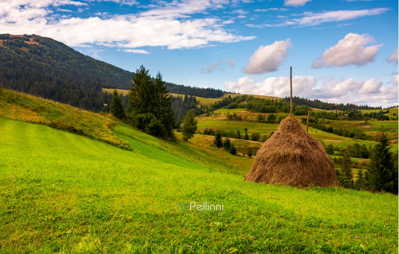 haystack on a grassy meadow in mountains. beautiful landscape under the azure sky with gorgeous cloudscape