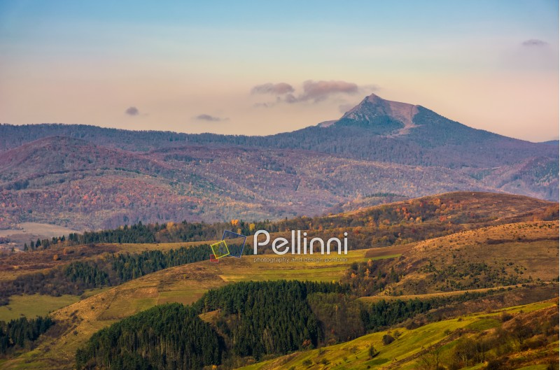 high mountain peak behind the hills with forest and meadows. gorgeous countryside landscape