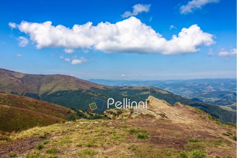 early autumn mountain landscape under the blue sky with clouds in morning light. meadow with wild grass on a slope.