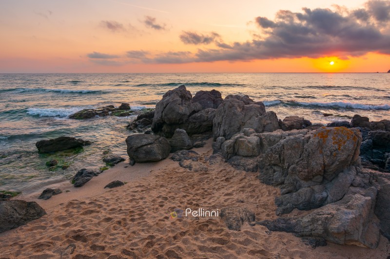 huge stones on a sandy beach at sunrise. wonderful summer vacation season at the black sea. calm waves washing the sand shore. nature background with cloudy sky. bulgaria travel photo