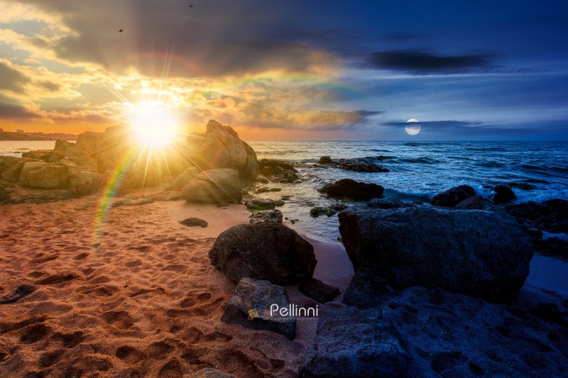 huge stones on a sandy beach. day meet night. epic summer vacati huge stones on a sandy beach. day meet night. epic summer vacation season at the black sea. sun and moon in harmony over calm waves washing the sand shore. nature background with cloudy sky