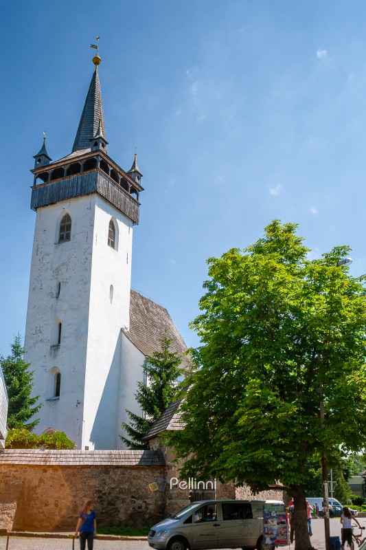 khust, ukraine - 16 jun 2012: medieval church of saint Elisabeth in downtown. building with tower behind stone masonry fence. gothic european architecture on a sunny day in summer