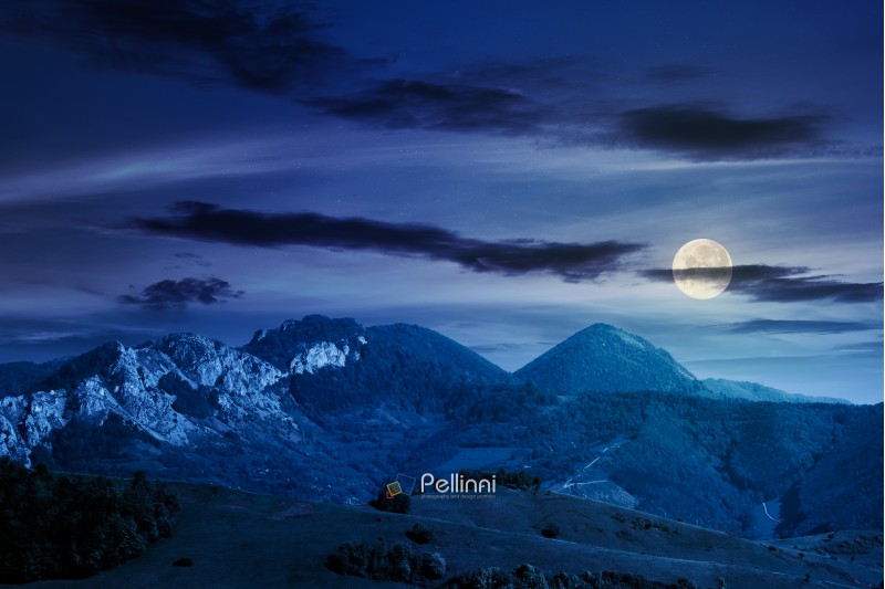 landscape in mountains with rocky formations. grassy meadows, forested hills and huge cliffs. wonderful nature scenery. beautiful weather at night in full moon light in springtime
