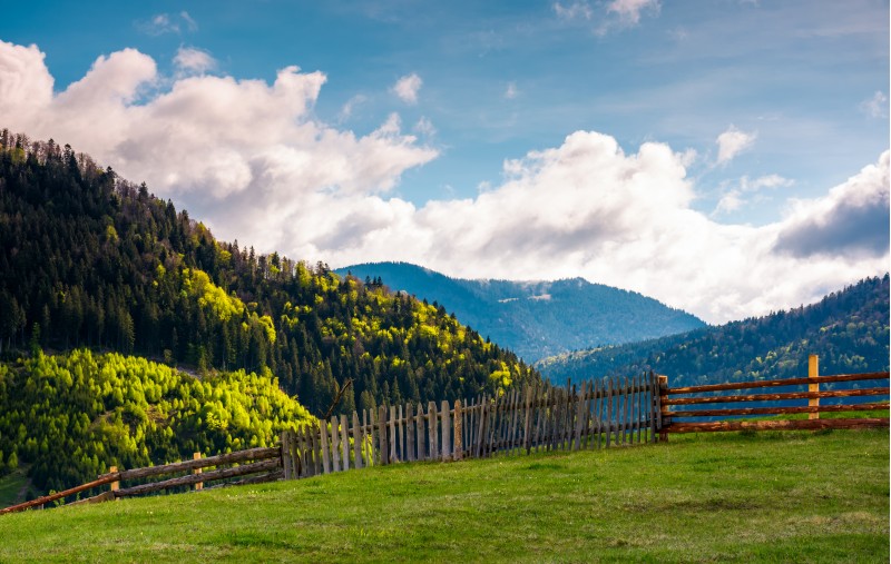 lovely rural landscape in Carpathians. wooden fence along the grassy hillside