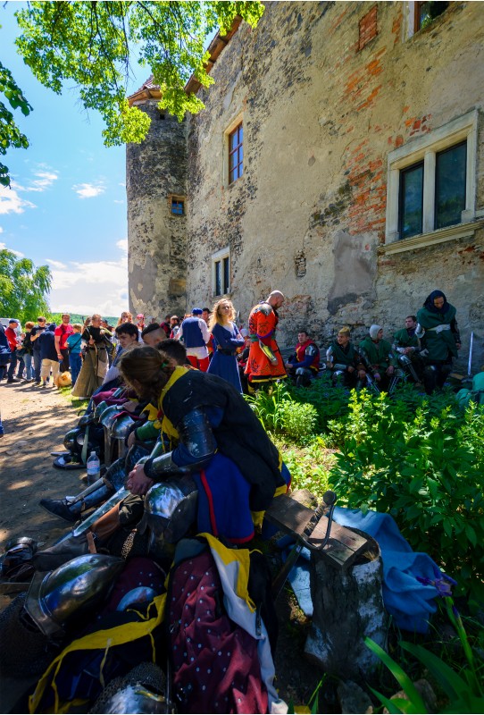 Chynadiyovo, Ukraine - May 27, 2017: medieval culture festival Silver Tatosh. Location St. Miklos Castle. Knight participants have rest under the castle wall in shade of tree