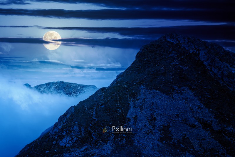 mountain landscape under cloudy sky at night. nature scenery travel background for hiking in summer vacation season in full moon light. scenic view of ridge with steep rocky slopes