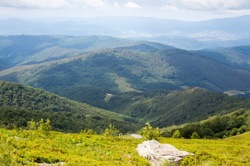 mountain landscape with cloudy sky in summer. view in to the valley. travel nature background with rocks among grass on the slope of a hill. beautiful alpine scenery of carpathian range