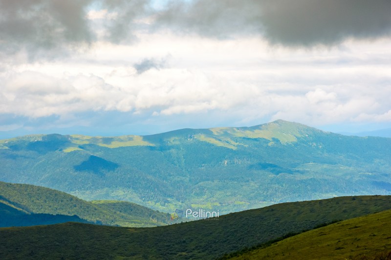 mountain landscape with green pikui peak under storm sky. beautiful summer scenery of carpathian watershed ridge. scenic view of valley in dappled light. outdoor adventure in highland of ulraine
