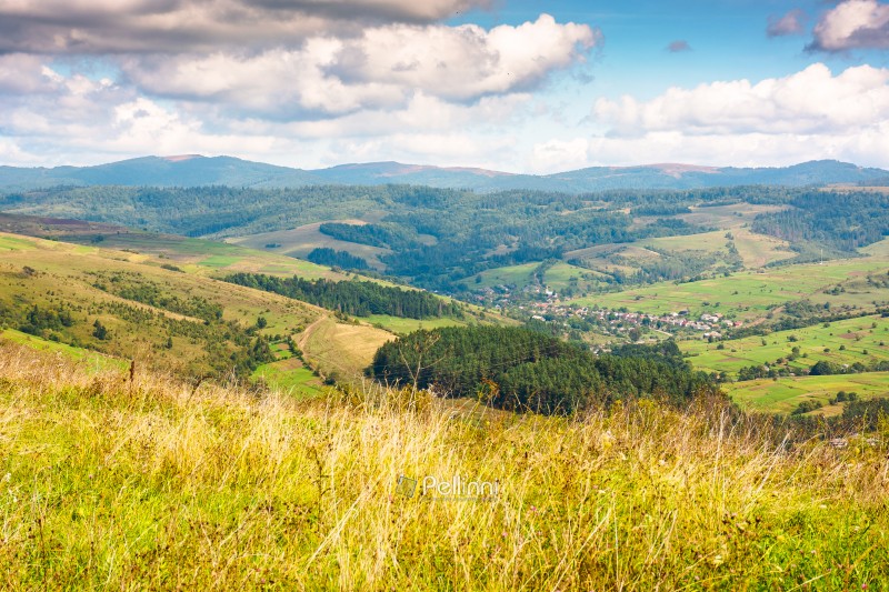 mountainous countryside landscape on early autumn forenoon. village near forest in the rural valley. sunny day with clouds on the sky