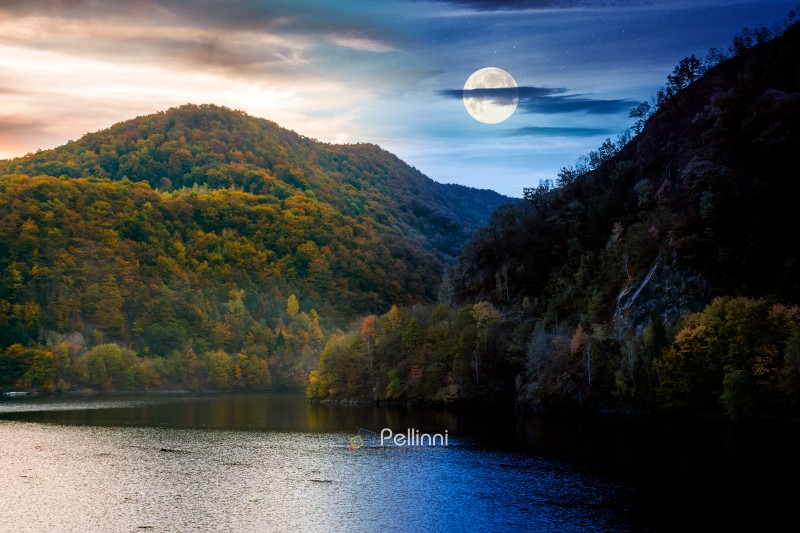 mountainous landscape with lake on autumn equinox. day and night mountainous landscape with lake on autumn equinox. day and night time change concept. forest on hills near the shore of river under sky with moon at twilight. beautiful view of stunning place
