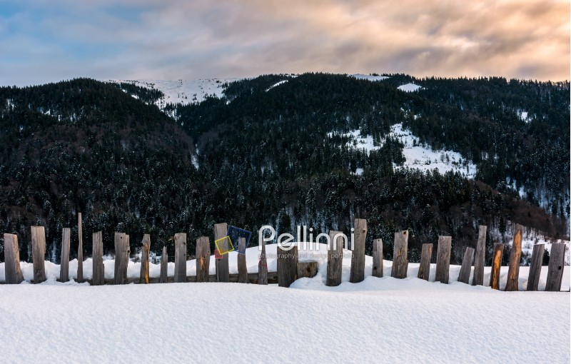 old wooden fence in snow on hillside. lovely mountainous rural scenery at sunrise