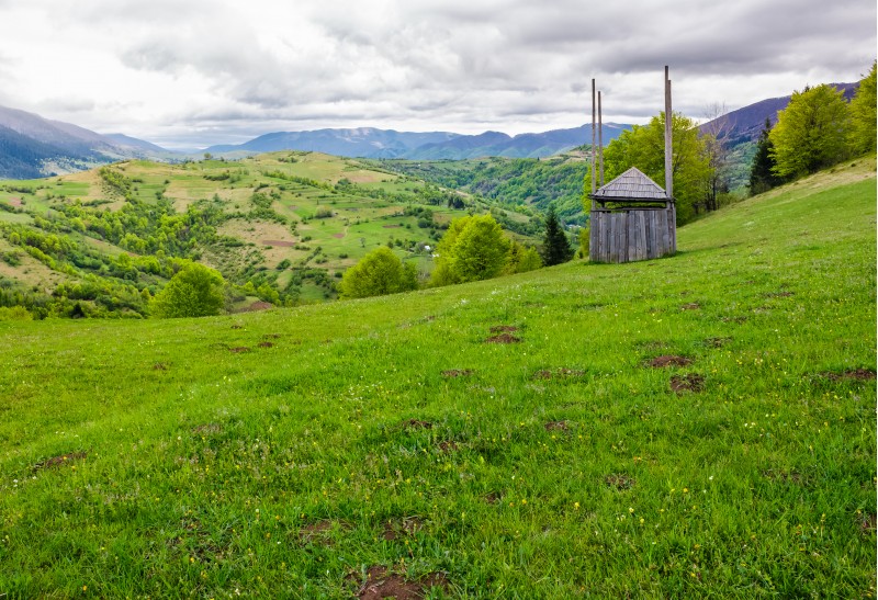 old wooden hay shed on grassy hillside. beautiful scenery of mountainous rural area in springtime