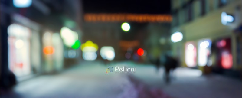 panorama of night street in winter. city light and glowing shop windows. christmas sales concept. blurred background