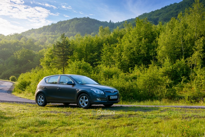 pepechyn, ukraine - 10 jun 2020: car on the countryside road. beautiful vacation destination in alpine region of eastern europe. green deciduous forest on the hill