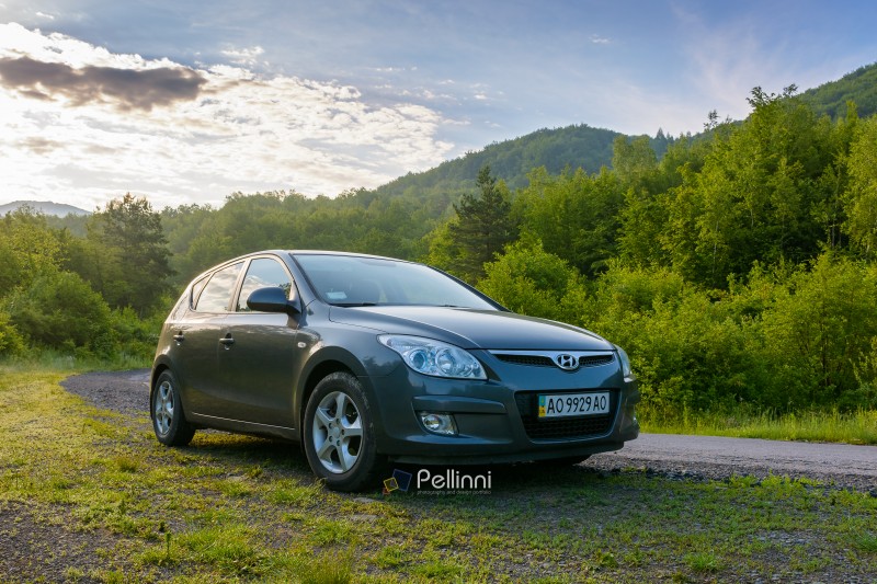pepechyn, ukraine - 10 jun 2020: car on the countryside road. spend unforgettable weekend in carpathian mountains. green deciduous forest on the hill