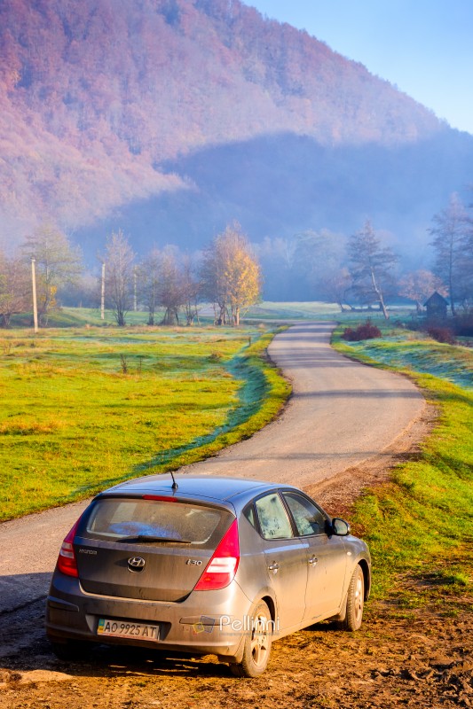 perechyn, ukraine - 10 nov 2020: car near asphalt road in autumn. trip through countryside mountain landscape of ukraine with morning fog. hyundai hatchback on the roadside near forest and field