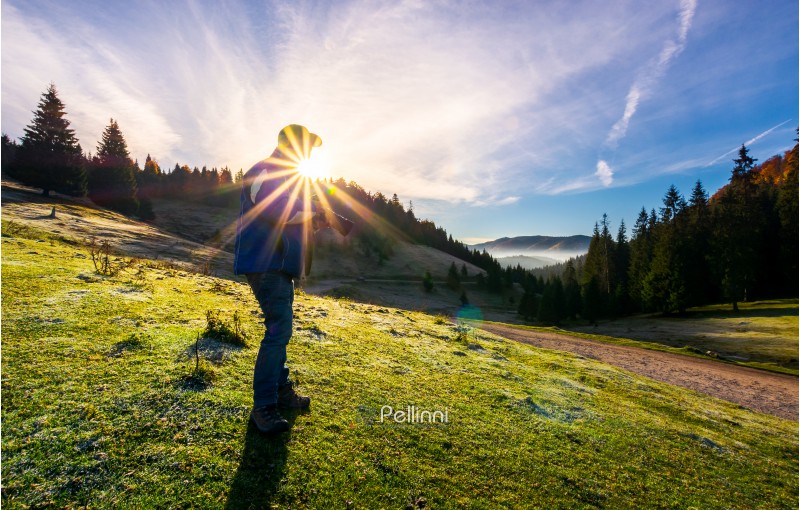 photographer in sunburst shooting foggy landscape. gorgeous scenery of Apuseni Natural Park in autumn at sunrise. wonderful adventure or job concept. blue sky with clouds
