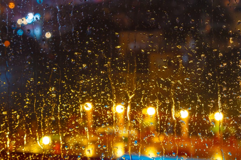 rain behind the hotel window. raindrop on the glass at night. blurred background abstract wallpaper