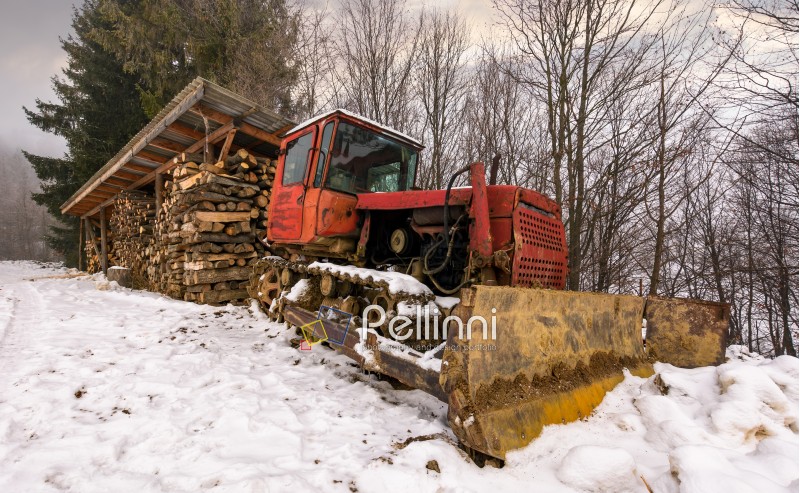 red dozer in snow near the wood shed. lovely rural scenery in forest