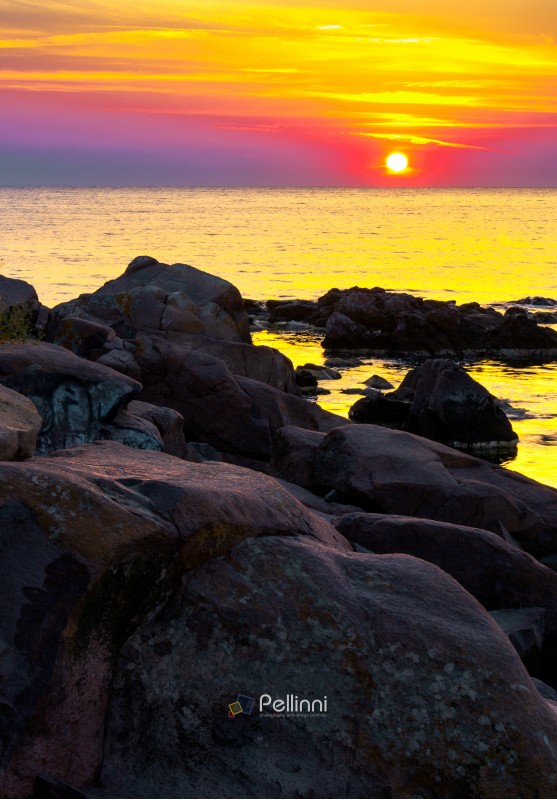 reddish sunrise over the sea with rocky shore. beautiful summer scenery and vacation concept