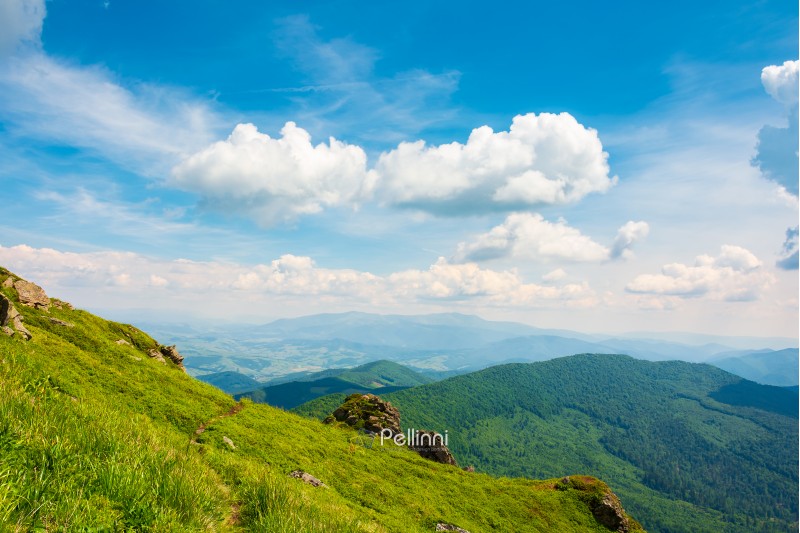 rock on grassy slope of a mountain. beautiful view from the top of a hill. wonderful summer landscape on a sunny day. beautiful clouds on a blue sky