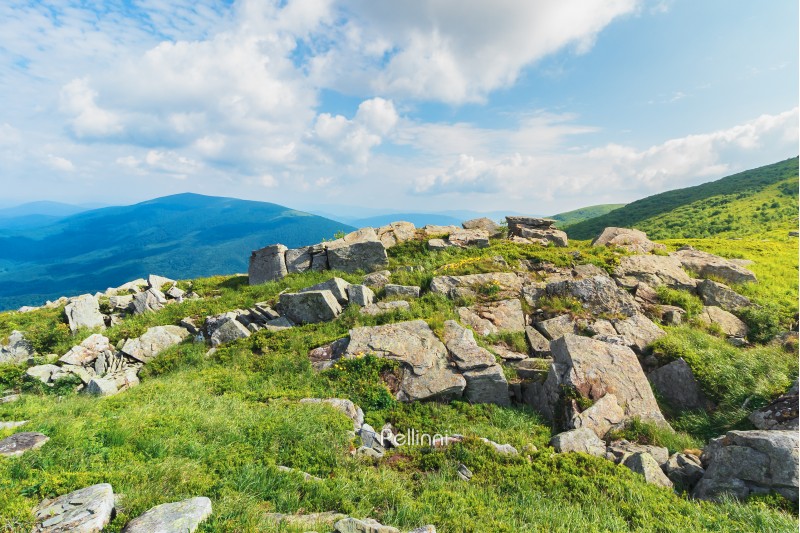 rocks on a grassy meadow in mountain. beautiful summer landscape. sunny weather with fluffy clouds