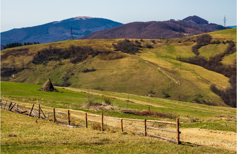 rural area on rolling hills in springtime. wooden fence and haystack near the road. lots of electric poles