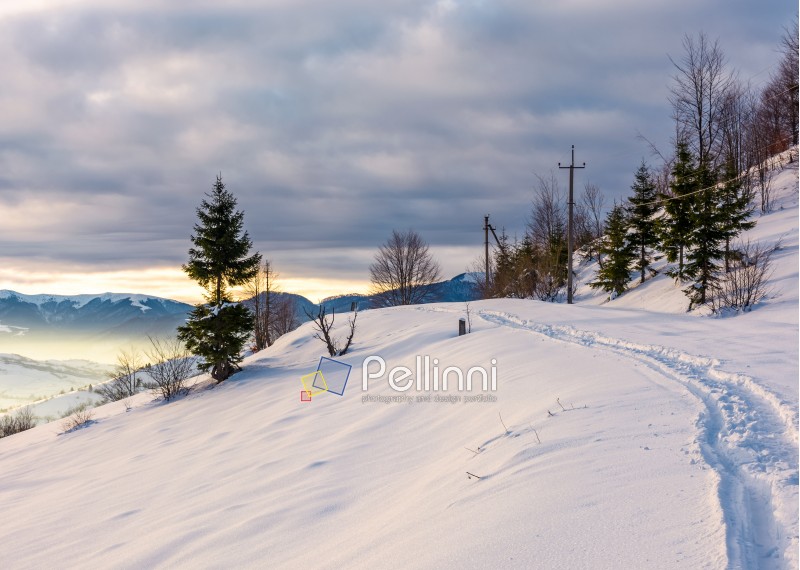 rural footpath through snowy hillside. beautiful scenery of mountainous countryside in winter