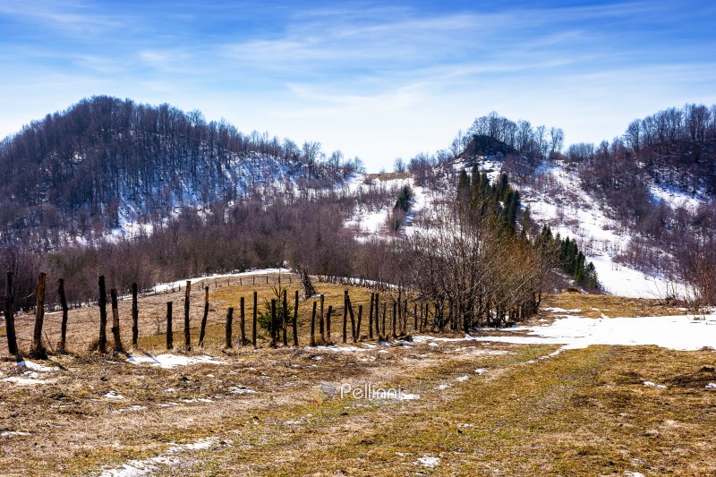 rural landscape of carpathian mountains in early spring under bl rural landscape of carpathian mountains in early spring under blue sky. snow covered hill with barbed wire fence on a sunny day. green environment sustainability and protection. background for earth day