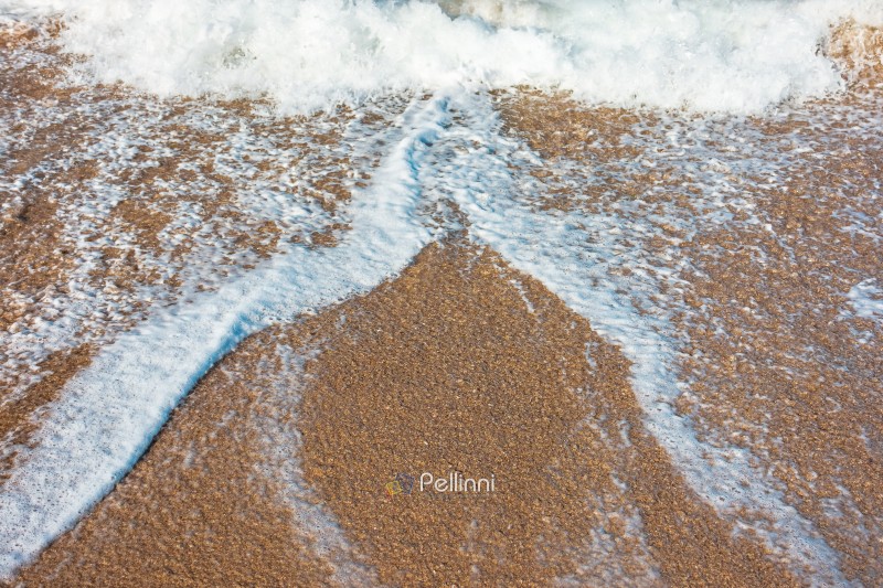 sea wave rolling foam on to the sandy beach. nature background o sea wave rolling foam on to the sandy beach. nature background on a sunny day. closeup texture of sea, sand, water and foam. seaside environment. tide on seashore