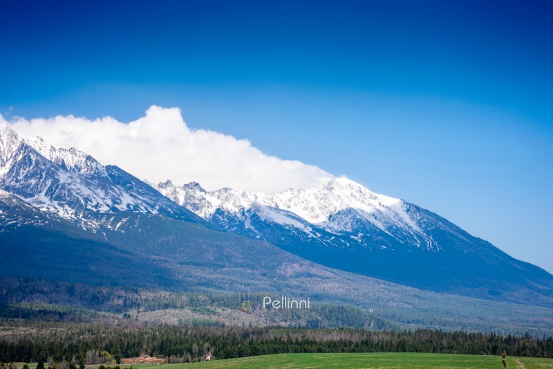 snow capped mountain peaks of high tatras in spring. scenic view of popular travel destination for remote trekking in slovakia, europe. alpine landscape with blue sky and clouds above the ridge