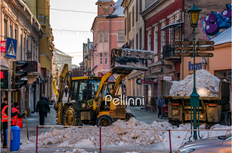 Uzhgorod, Ukraine - January 19, 2017: snow removal on streets of old town. people remove snow huge amount of snow with the help of shovels and tractor