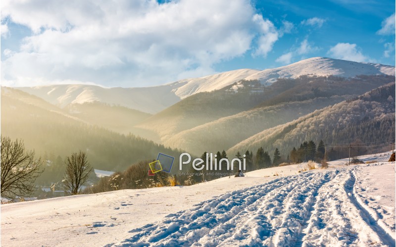 snowy mountain ridge above the rural area. lovely countryside winter scenery.