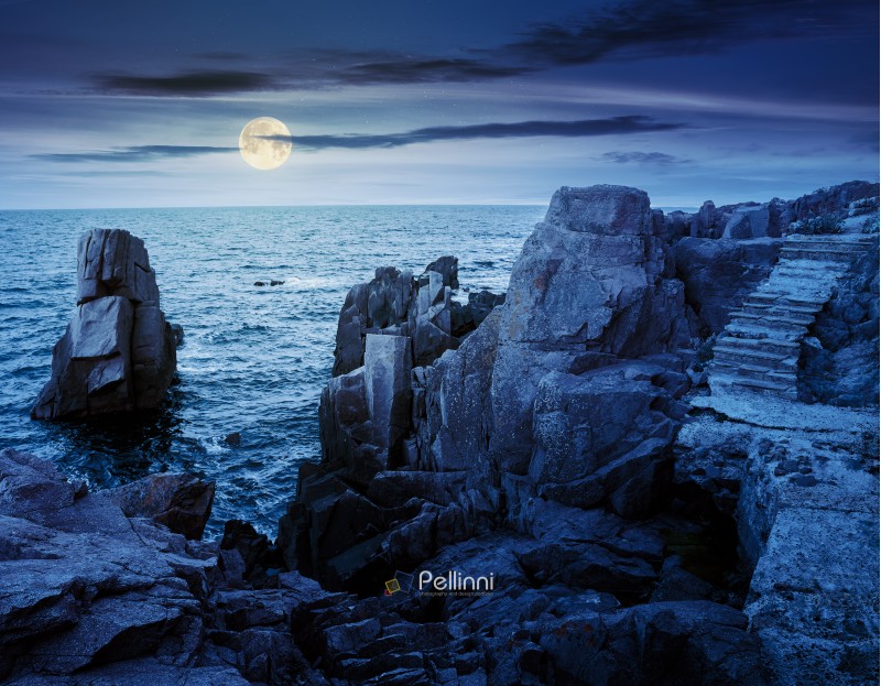 stone steps on rocky cliffs above the sea. gorgeous cloudscape at night in full moon light