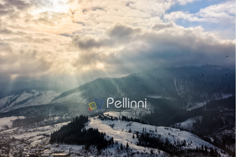 stormy winter sky over village at the foot of the mountain in fog