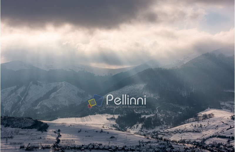 sunbeams through clouds over the snowy mountains. beautiful countryside scenery in winter