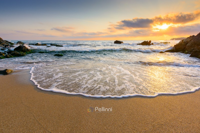 sunrise on the beach. beautiful summer landscape for vacation at the sea. rocks on the sand. calm waves on the water. sun behind clouds on the sky. wide panoramic view of bamboo beach in sozopol